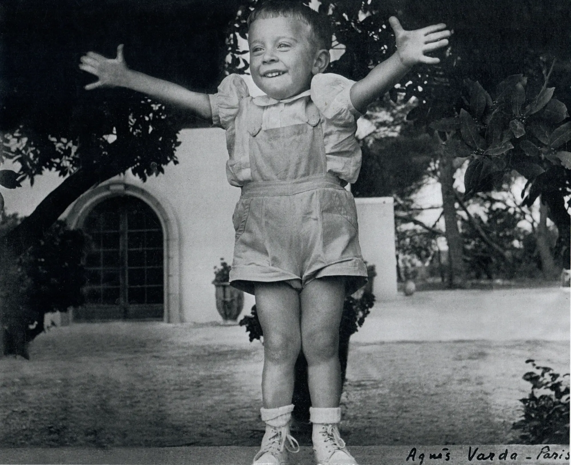 Édouard enfant, bras ouverts devant la bergerie - photographie d'Agnès Varda, 1952