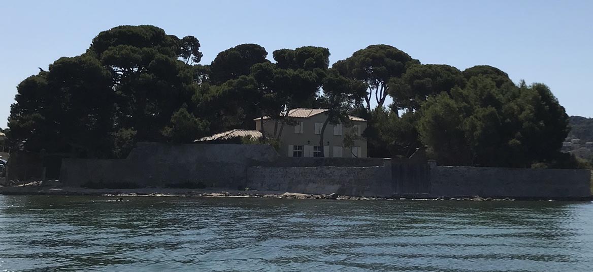 Le domaine vu depuis l'étang, derrière son mur de pierre et ses grands pins