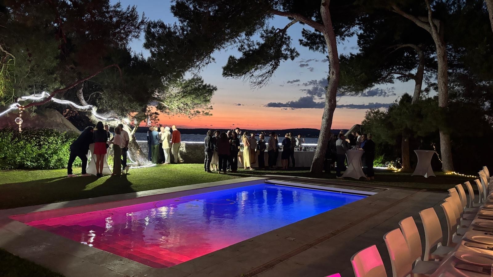 Soirée d'entreprise au bord de la piscine illuminée, au coucher du soleil sur l'étang